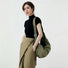 Woman in black turtleneck and khaki skirt with large olive green shoulder bag