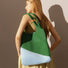 Side view of color-block green and light blue knitted bag highlighting flexible structure and artistic style.