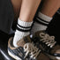 Model wearing a pair of black Athletic Striped Slouch Socks, ideal for everyday outfits and sneakers.