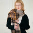 Model wearing cozy Autumn Ember Plaid Scarf, a wool blend in warm brown, gold, and cream tones in yellow.