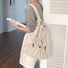 Model wearing beige foldable backpack featuring ultralight polyester and secure drawstring storage.