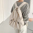 Model wearing beige foldable backpack, perfect for city travel.
