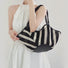 Model carrying the Black And White Striped Basket Bag on her shoulder, easy for commuting and weekends.