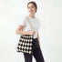 Model styling a black and beige argyle pleated knit bag for a minimalist style