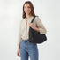Model wearing a black quilted puffy hobo bag as shoulder bag for an urban chic look.