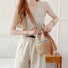Model wearing the colorful woven straw bucket bag as crossbody.