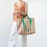 Model carrying a khaki striped tote bag handheld, easy for commuting and weekends.