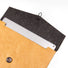 Tan Tyvek laptop sleeve with a dark felt interior, button and cord closure, holding a silver laptop.