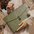 Model carrying a Buttoned Envelope Laptop Sleeve in olive green, easy for commuting and weekends.