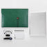 Folded view of Green PU leather file folder with button closure, next to a laptop, glasses, pen, phone, and watch.