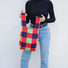 Model carrying a red plaid tote bag handheld, easy for commuting and weekends.