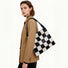 Model wearing a black and white checkered woven leather shoulder bag, ideal for stylish office commuting.