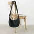 The classic black ruched crescent bag displayed on a wooden chair.