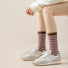 Model wearing a pair of Chromatic Stripe Socks in burgundy, great for daily wear and lounging.