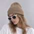 Model wearing a neutral khaki brown knitted acrylic beanie for a relaxed casual outfit.