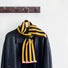 Angled view of ColorPop striped polyester scarf, black and yellow with pink tips, draped over a black jacket.
