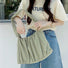 Close-up of model holding the green pleated bag; highlighting the durable ruched design and spacious interior for daily essentials.