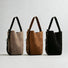Group shot of the convertible suede bucket bag in grey, brown, and black.
