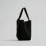 Side view of the black convertible suede bag, highlighting its clean minimal design.