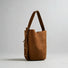 Close-up on the side profile and unique buckle of the brown suede convertible hobo.