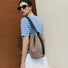 Model wearing the grey suede bag as a sling style, showing its adjustable strap.