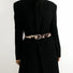 Close-up of cow print belt on a black coat; trendy animal print design suited for winter street style and layering.