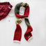 Angled view of Cozy Patch Skinny Scarf: Red, olive, and tan color block wool blend scarf with fringe ends.