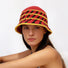 Model wearing the red knitted bucket hat, with yellow and black cross striped.
