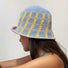 Model wearing the blue knitted bucket hat, with pink and yellow cross striped pattern.