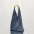 Front view of Denim shoulder bag with a unique triangular shape and braided straw-look handles.