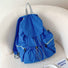 Blue nylon ultralight backpack with drawstring and snap closure, front drawstring pocket, and side zip pockets.