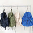 Four ultralight nylon drawstring backpacks in black, olive green, beige, and royal blue, hanging on a rack.