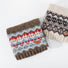 Two folded wool-acrylic Fair Isle pattern scarves. One is brown with red and blue accents, the other is cream with brown and gray.