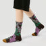 Model wearing a pair of Fantasy Garden socks, with purple, brown, green, and white floral patterns.