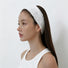 Side profile of a model showing the comfortable fit of the white lace hairband tucked behind the ear.