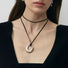 Model wearing silver fluid oval pendant on black leather cord, contemporary artistic jewelry styling