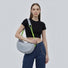 Model wearing the grey nylon crescent bag with knotted neon green straps.