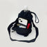 Close-up of the functional drawstring closure and front zip pocket of a technical fabric bottle bag.