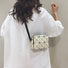 GeoChic crossbody bag in cream PU leather with geometric black lines, worn over a white shirt.