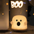Front view of Glowing white plastic ghost lamp with black eyes and mouth.