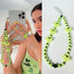 Model grabing a phone with lime green heart beat phone charm.