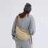 Model wearing a khaki nylon sling bag as crossbody, ideal for a cozy, casual style.
