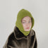 Model styling the green knitted balaclava for a cozy winter look.