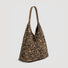 Side perspective of the slouchy leopard print suede shoulder bag.