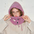 Close-up of a mauve pink buttoned balaclava hat being adjusted, highlighting the soft-textured wool blend.