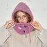 Close-up of a mauve pink buttoned balaclava hat being adjusted, highlighting the soft-textured wool blend.