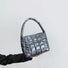 Angled view of Metallic Glow Quilted Bag in gray, great for everyday carry and travel.
