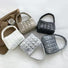 Front view of Five metallic quilted polyester bags in white, silver, gold, black, and dark gray.