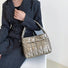 Model carrying a gold polyester bag handheld, great for daily carry and travel.