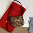 Angled view of Mini leopard print vegan suede saddle bag with black strap and magnetic flap.